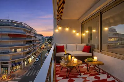 a balcony with a couch and tables and a city at Luxury Maubourg - Vue mer - Croisette 50m plage - Clim - terrasse in Cannes