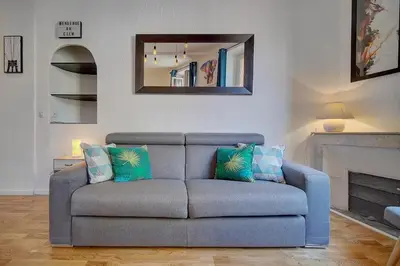 a blue couch in a living room with a mirror at le Clem - 100m des plages - Suquet - Verrière Côte d’Azur in Cannes