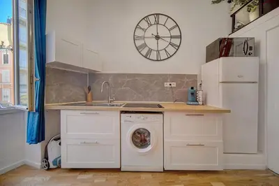 a kitchen with a washing machine and a clock on the wall at le Clem - 100m des plages - Suquet - Verrière Côte d’Azur in Cannes