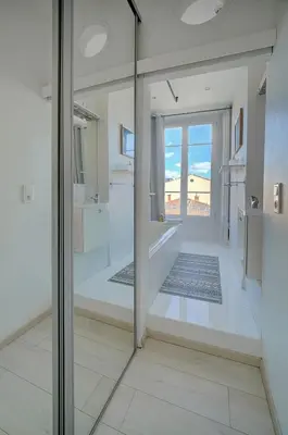 a room with a glass door with a view of the ocean at IMMOGROOM - Bourgeois building - Quiet - Parking - Sea view in Cannes