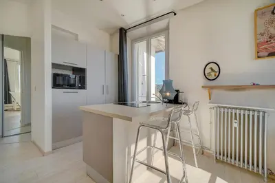 a kitchen with a counter and two stools at IMMOGROOM - Bourgeois building - Quiet - Parking - Sea view in Cannes
