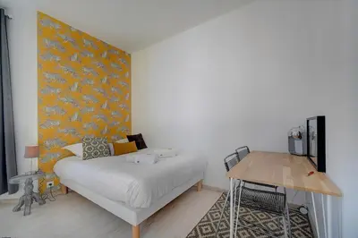 a bedroom with a bed with a yellow wall at IMMOGROOM - Bourgeois building - Quiet - Parking - Sea view in Cannes