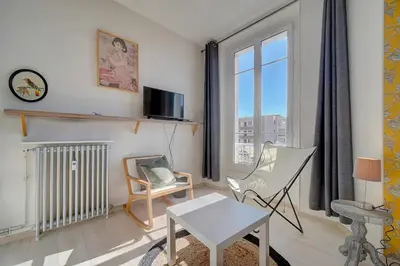 a living room with a table and chairs and a window at IMMOGROOM - Bourgeois building - Quiet - Parking - Sea view in Cannes