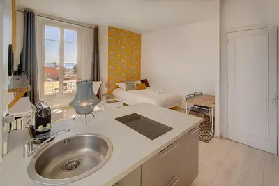 a kitchen with a sink and a living room at IMMOGROOM - Bourgeois building - Quiet - Parking - Sea view in Cannes