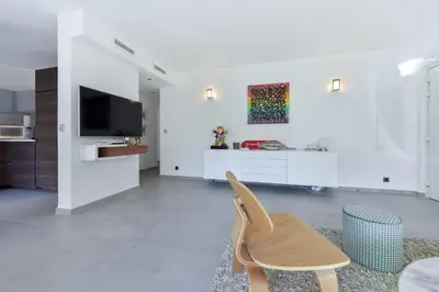 a white living room with a chair and a tv at 3-Br Apartment 3 minutes to the Croisette in Cannes