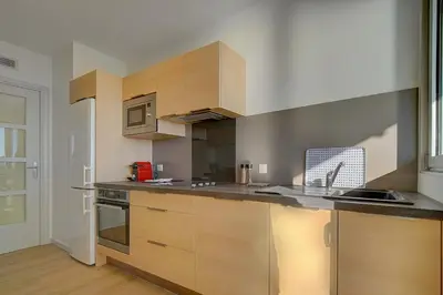a kitchen with wooden cabinets and stainless steel appliances at IMMOGROOM- Incredible View -4- Big Terrace - AC - Parking in Cannes