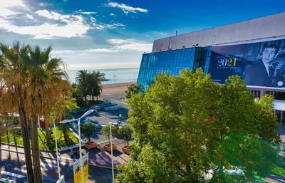 a building with a billboard on it next to a beach at LEM5D - Palmes d'Or Properties in Cannes