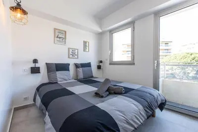 a bedroom with a large bed with a stuffed animal on it at LB Vacation Rentals I Cannes Center, Renovated Apartment with Balcony, Ideal for Holidays or Congress! in Cannes