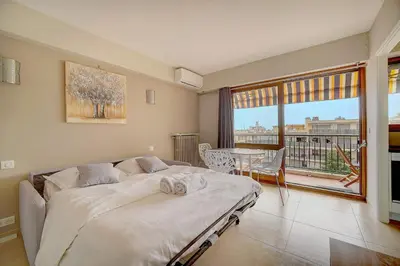 a bedroom with a bed and a large window and a table at IMMOGROOM - Very Pleasant and Bright - Cozy - Shops in Cannes