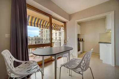 a dining room with a table and chairs and a balcony at IMMOGROOM - Very Pleasant and Bright - Cozy - Shops in Cannes