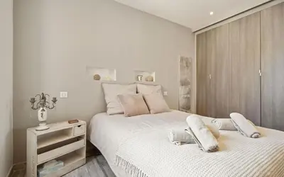 a white bedroom with two beds and a night stand at Duplex ForVille in Cannes