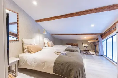 two beds in a room with two windows at Duplex ForVille in Cannes