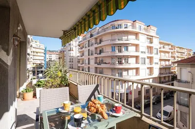 a table with food on a balcony with a building at Majestic Apartment in Cannes
