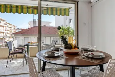 a dining room with a table and chairs on a balcony at Majestic Apartment in Cannes