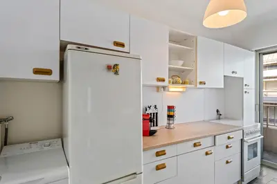 a kitchen with white cabinets and a refrigerator at Majestic Apartment in Cannes