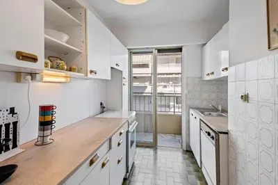 a kitchen with white cabinets and a wooden counter top at Majestic Apartment in Cannes