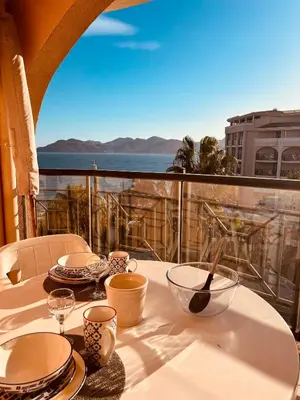 a table with plates and glasses on a balcony at Résidence La Palme d'Azur - Petersen App 610 in Cannes