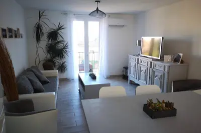 a living room with a television and a table and chairs at Jolie petite Maison de Charme dans quartier boisé in Vallauris
