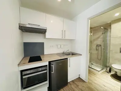 a kitchen with white cabinets and a sink and a shower at Résidence 41 Léon Noel in Cannes