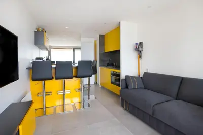 a living room with a couch and a kitchen at Appartement Wester - Welkeys in Cannes