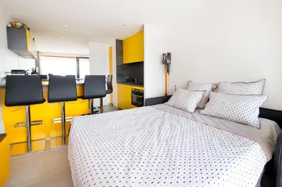 a bedroom with a bed and a kitchen with yellow cabinets at Appartement Wester - Welkeys in Cannes
