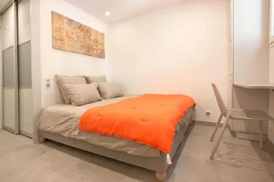 a bedroom with a bed with an orange blanket on it at Appartement Wester - Welkeys in Cannes
