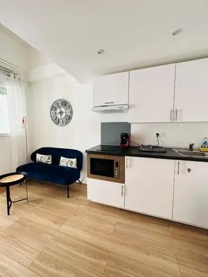 a kitchen with white cabinets and a blue couch at Résidence Delattre in Cannes