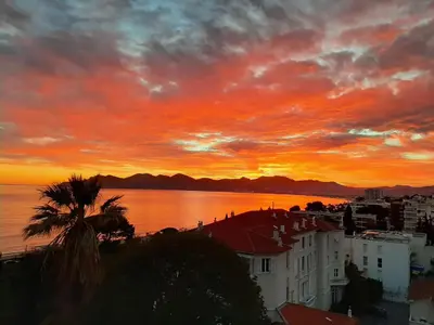 a sunset over a city and the water with buildings at Plages du Midi, Superbe Vue Mer, Grand Confort, 4 pers in Cannes