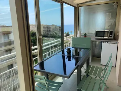 a balcony with a glass table and chairs and the ocean at Appartement rooftop, première ligne, vue mer, 50m de plage du Midi in Cannes