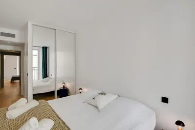 a bedroom with a large white bed and a mirror at Gold Apartment in Cannes