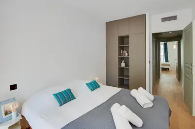 a white bedroom with a large white bed with blue pillows at Gold Apartment in Cannes