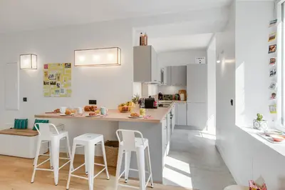 a kitchen with white cabinets and a counter with stools at Gold Apartment in Cannes