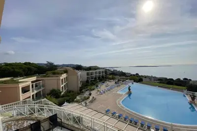 a view of a swimming pool with chairs and the ocean at C021 Lumineux appartement avec Terrasse et Piscine in Cannes