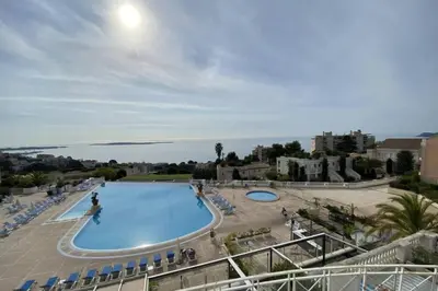 a large swimming pool with chairs and the ocean at C021 Lumineux appartement avec Terrasse et Piscine in Cannes