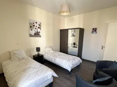 a bedroom with two beds and a chair and a mirror at Cannes Centre, 3 Chambres, Plage et La Croisette à 50m in Cannes