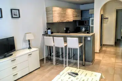 a kitchen with a bar with stools and a television at C038-Elegant apt a few steps from beaches - Le Suquet in Cannes