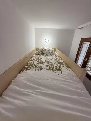 a bed in a small room with a light on it at Un Studio de Charme Vue Mer & Piscine d'Exception in Cannes