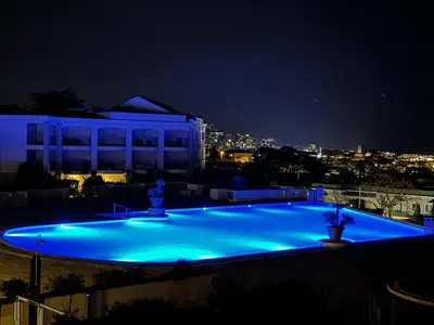 a large swimming pool lit up at night at Un Studio de Charme Vue Mer & Piscine d'Exception in Cannes