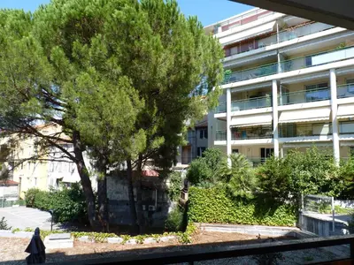 a woman walking past a tree in front of a building at Apartment 2 pièces Cannes Centre in Cannes