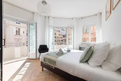a white bedroom with a bed and windows at 3-Br apartment in the Golden Square in Cannes