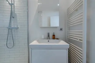 a white bathroom with a sink and a shower at 3-Br apartment in the Golden Square in Cannes