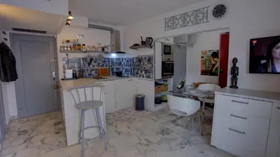 a kitchen with white cabinets and a counter and chairs at Les Tambourins Studio 19 - 3 étoiles in Cannes