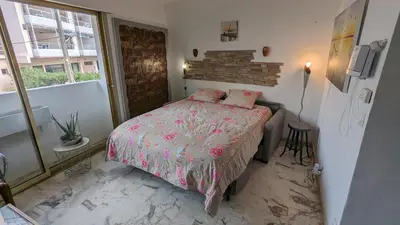 a bedroom with a bed with a pink comforter at Les Tambourins Studio 19 - 3 étoiles in Cannes