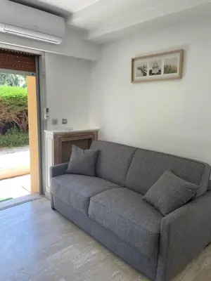 a gray couch in a living room with a window at NICE FLAT WITH GARDENS Limites cannes juste 10 MNS CROISETT in Le Cannet