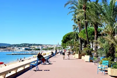 a group of people walking on a sidewalk near the beach at NICE FLAT WITH GARDENS Limites cannes juste 10 MNS CROISETT in Le Cannet