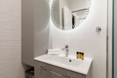 a white bathroom with a sink and a mirror at Fettolina in Cannes