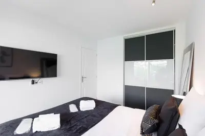 a white bedroom with a bed and a tv at Phoenix YourHostHelper in Cannes