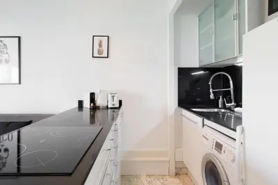 a kitchen with white cabinets and a washer and dryer at Phoenix YourHostHelper in Cannes
