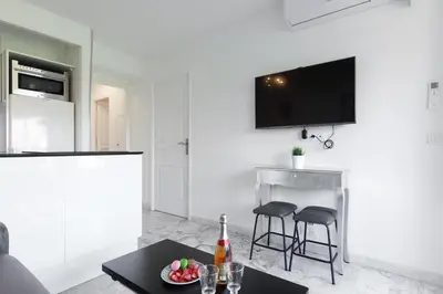a white living room with a table and two bar stools at Phoenix YourHostHelper in Cannes