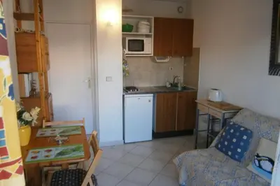 a small kitchen with a white refrigerator and a table at Comfortable Flat With Balcony Cannes City Centre in Cannes